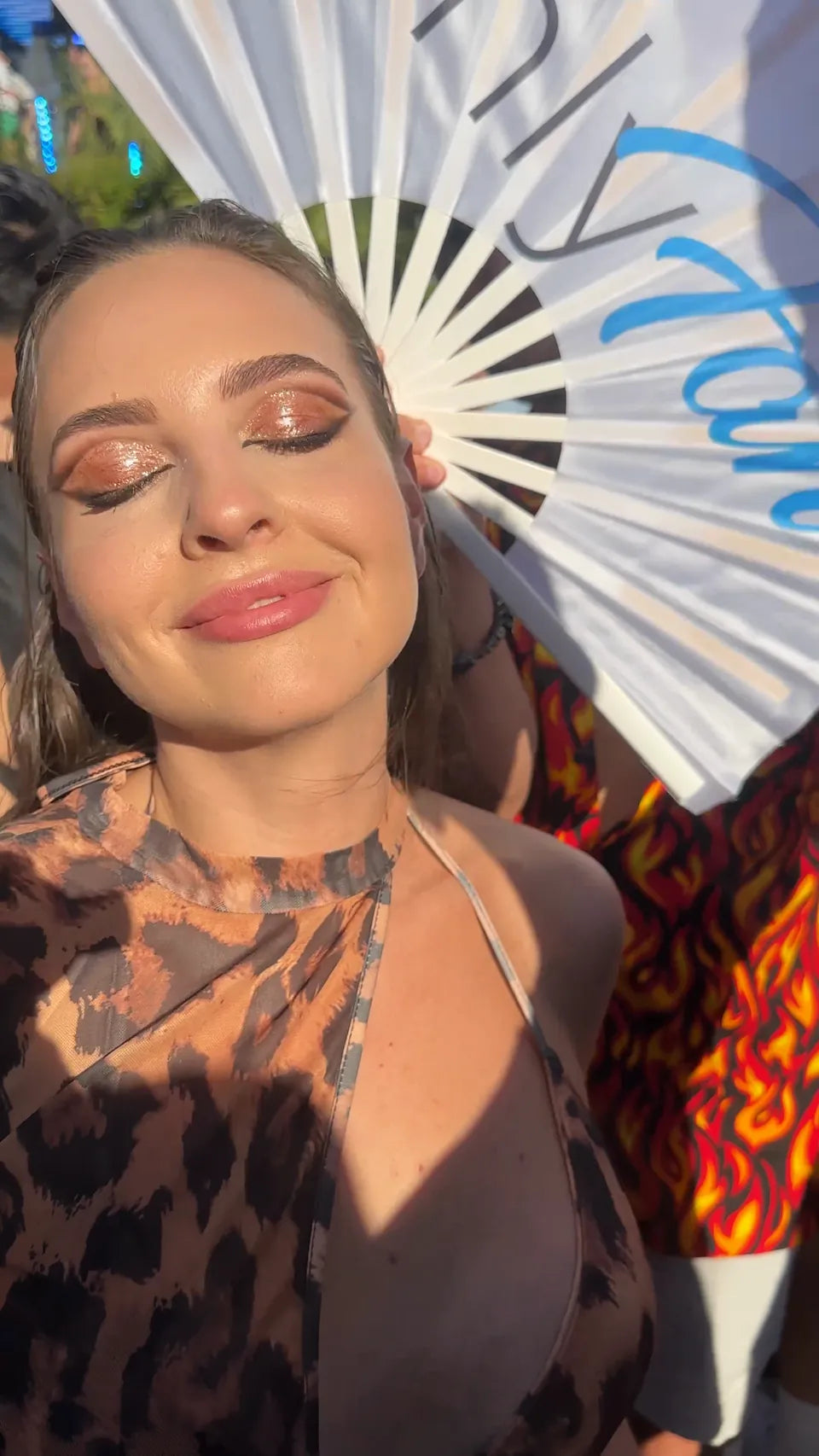 Copper-toned shimmer eyelids catching the sunlight at an outdoor festival
