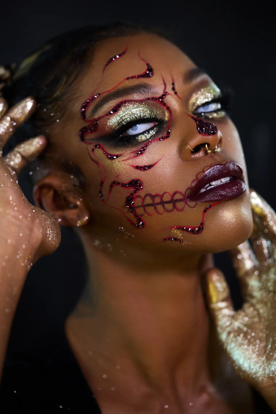 Portrait of jeweled skull makeup with luminous gold eyelids and burgundy details