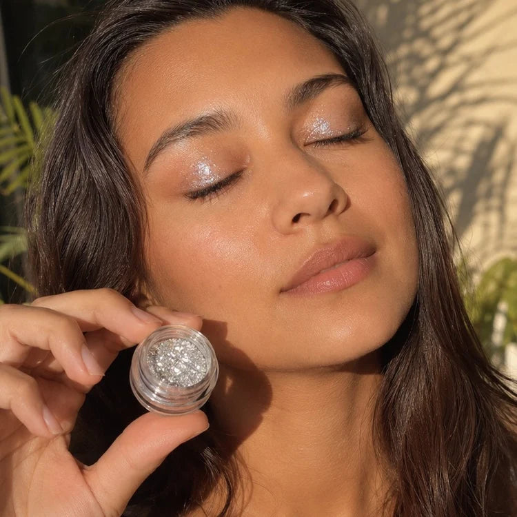Campaign portrait showing silver shimmer eye makeup and an open pigment jar